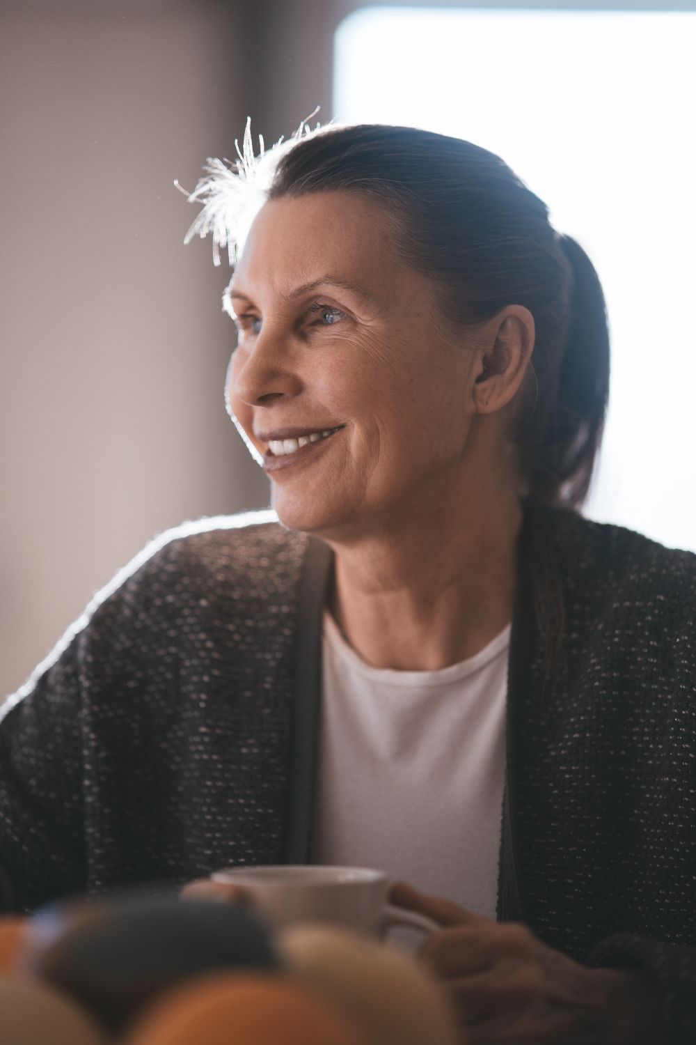 A smiling woman in a cosy cardigan in warm natural light